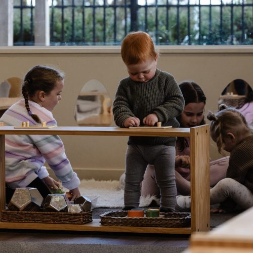 Children engaged in Montessori play activities at preschool, including building and exploring materials together in an early learning centre environment.